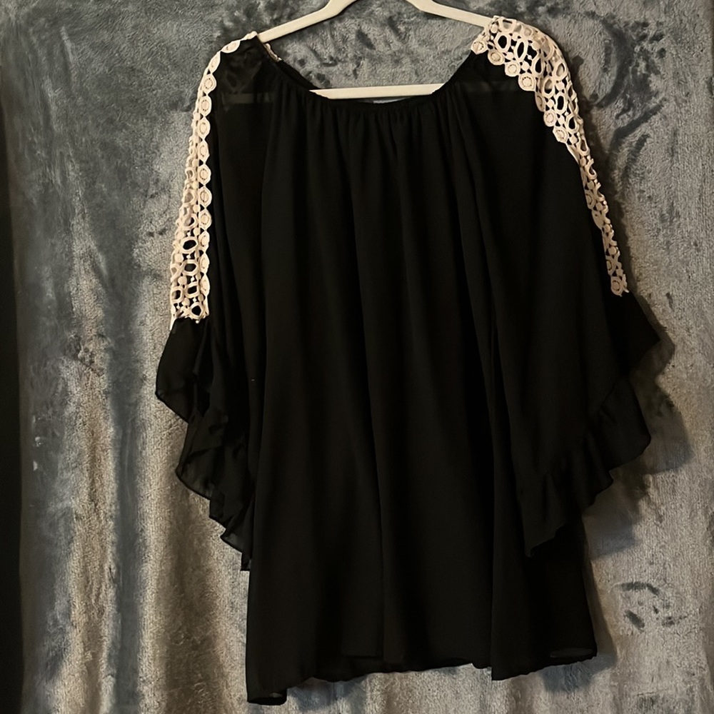 Black mini dress with white crochet detail on sheer sleeves that are oversized